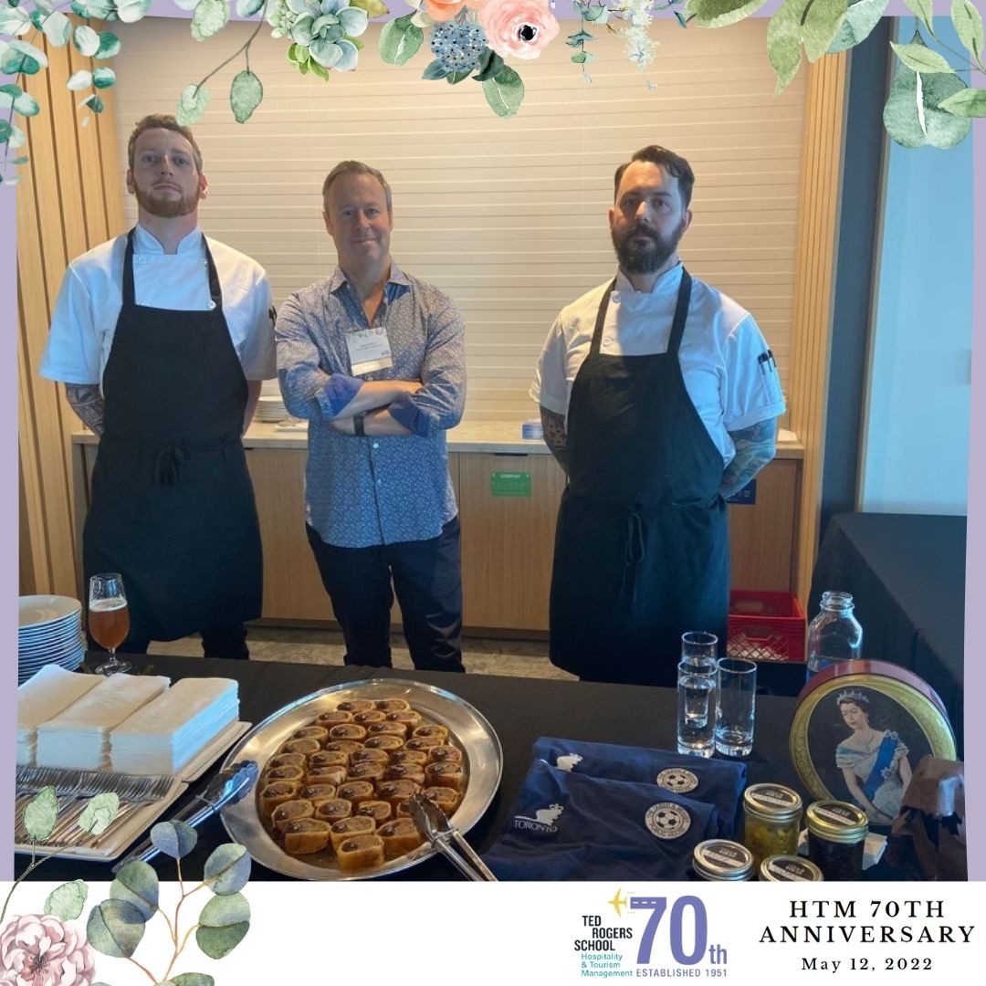 Three employees from a catering company at HTM's 70th anniversary event standing with their food.